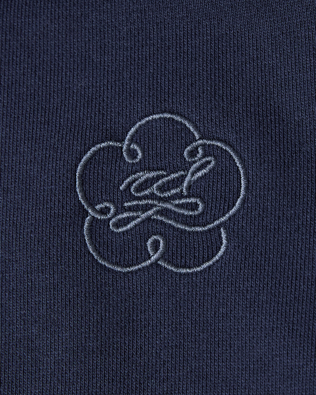 Close-up of the Sundae School NAVY HESTER QUARTER ZIP, a vintage-inspired cotton pullover with an embroidered blue cloud or flower design, featuring an oversized quarter zip and a subtle stash pocket.