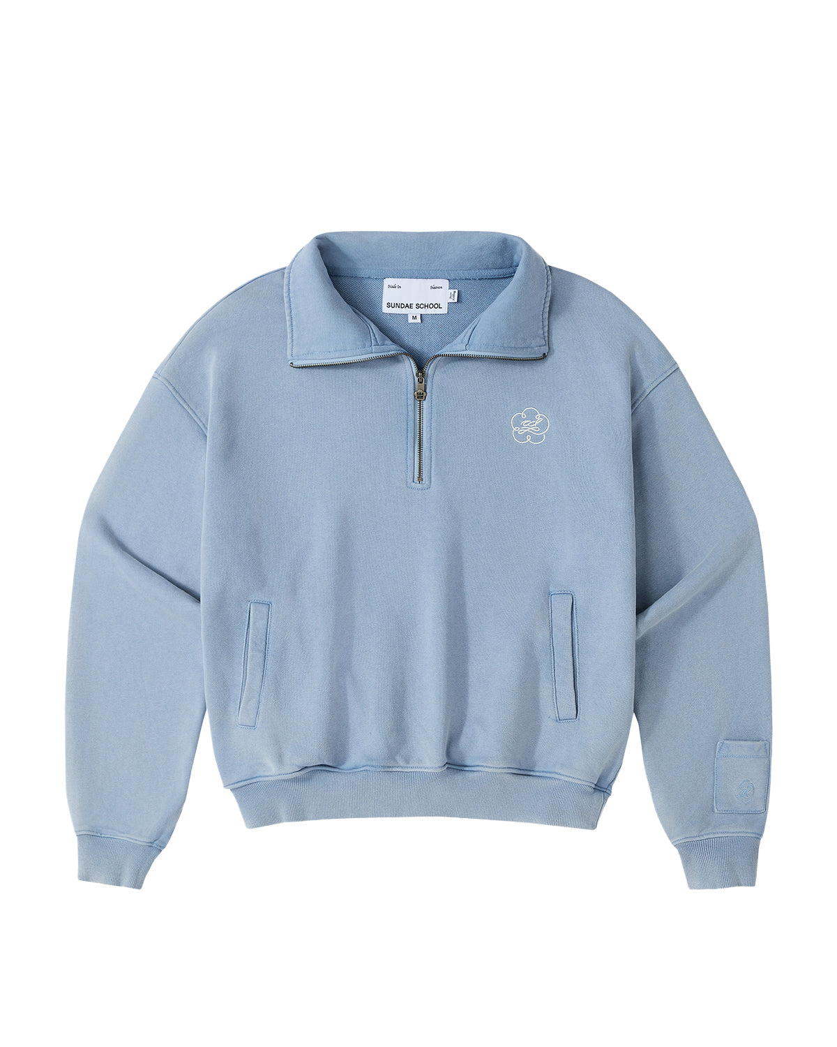 Introducing the SKY BLUE HESTER QUARTER ZIP by Sundae School—a light blue, long-sleeve oversized pullover featuring a quarter zip, funnel neck collar, and front chest logo. Designed with two side pockets, ribbed cuffs and hem, and a visible Sundae School label inside the collar, this vintage cotton piece seamlessly combines comfort with classic style for an effortlessly timeless look.