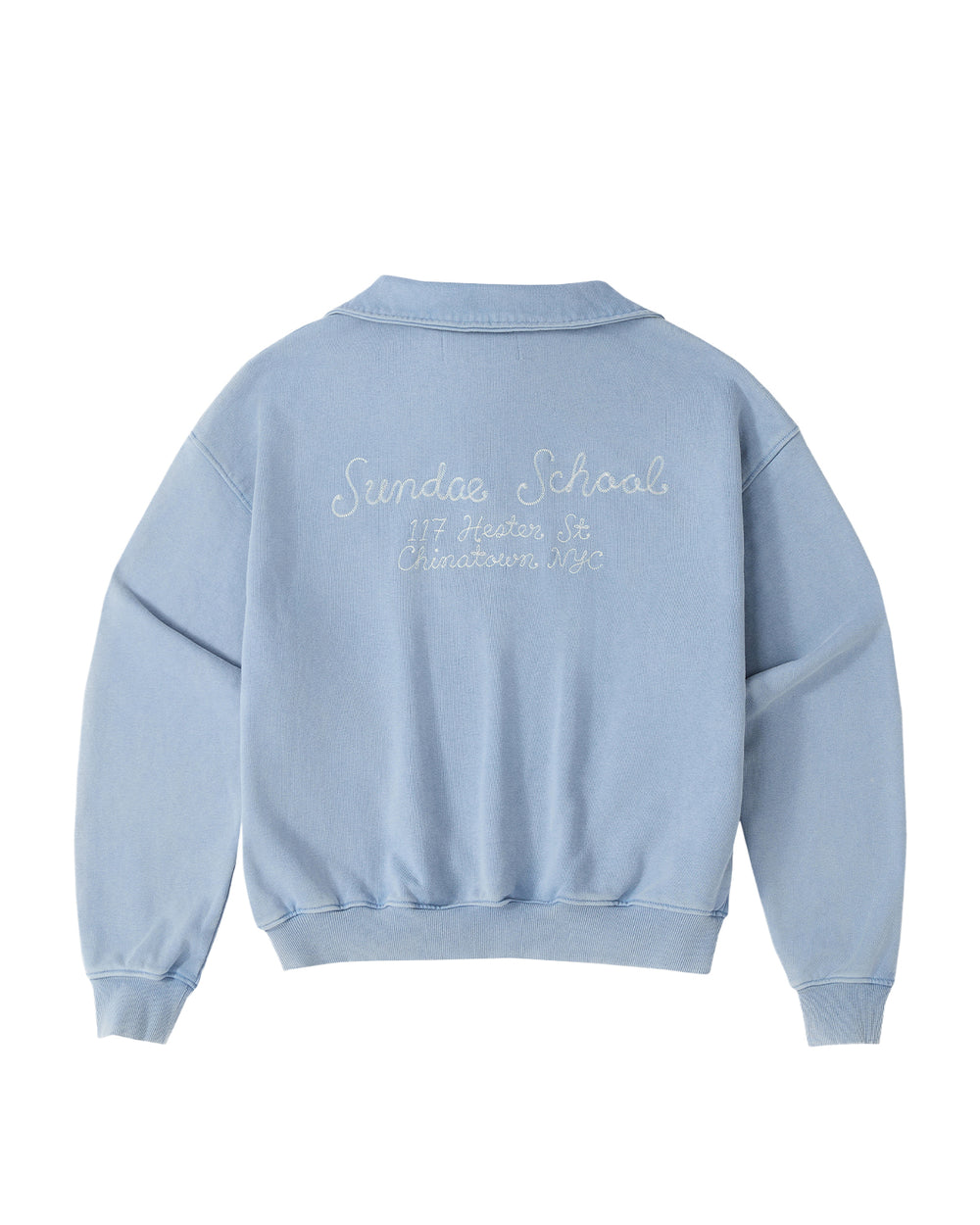 The SKY BLUE HESTER QUARTER ZIP by Sundae School is an oversized, vintage-inspired cotton pullover sweatshirt in light blue. It features a quarter zip with a funnel neck collar, long sleeves, ribbed cuffs and hem, and white embroidery on the back that reads “Sundae School, 117 Hester St, Chinatown NYC.”.