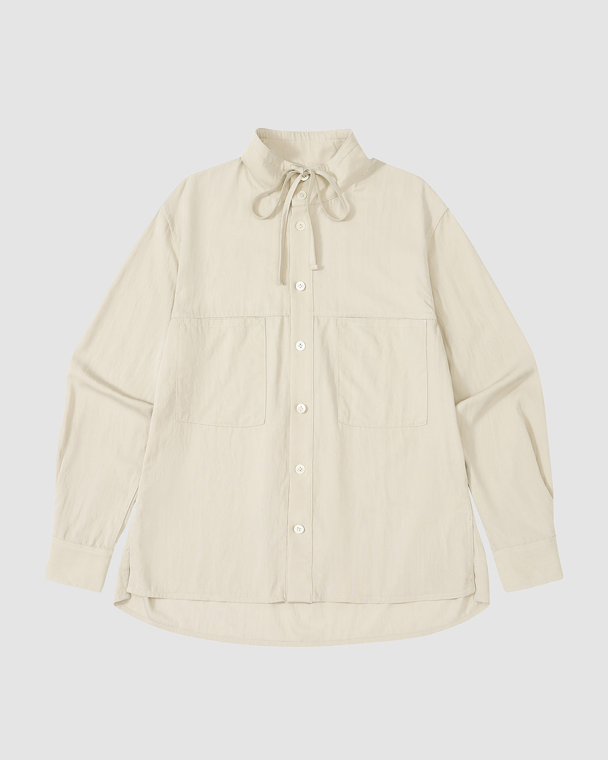 The IVORY HIGH NECK TIE SHIRT by Sundae School is a cream, long-sleeve summer-weight top with a convertible high neck, oversized chest pockets, and a drawstring collar, shown laid flat on a white background.