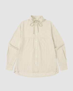 The IVORY HIGH NECK TIE SHIRT by Sundae School is a cream, long-sleeve summer-weight top with a convertible high neck, oversized chest pockets, and a drawstring collar, shown laid flat on a white background.