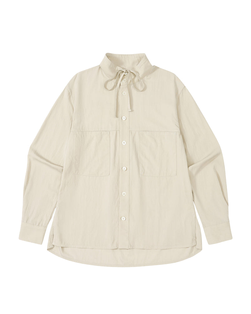 The IVORY HIGH NECK TIE SHIRT by Sundae School is a cream-colored, long-sleeve button-up featuring oversized chest pockets and a tie at the collar, crafted in a lightweight summer fabric and photographed laid flat against a white background.