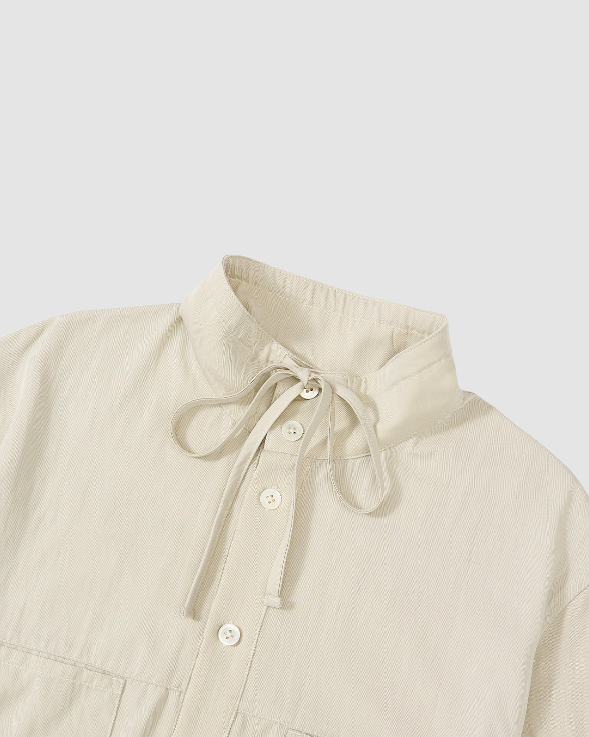 The Sundae School IVORY HIGH NECK TIE SHIRT features a cream convertible design with a stand collar, button-down front, tie-up neck detail, and summer-weight fabric, shown against a plain light background.