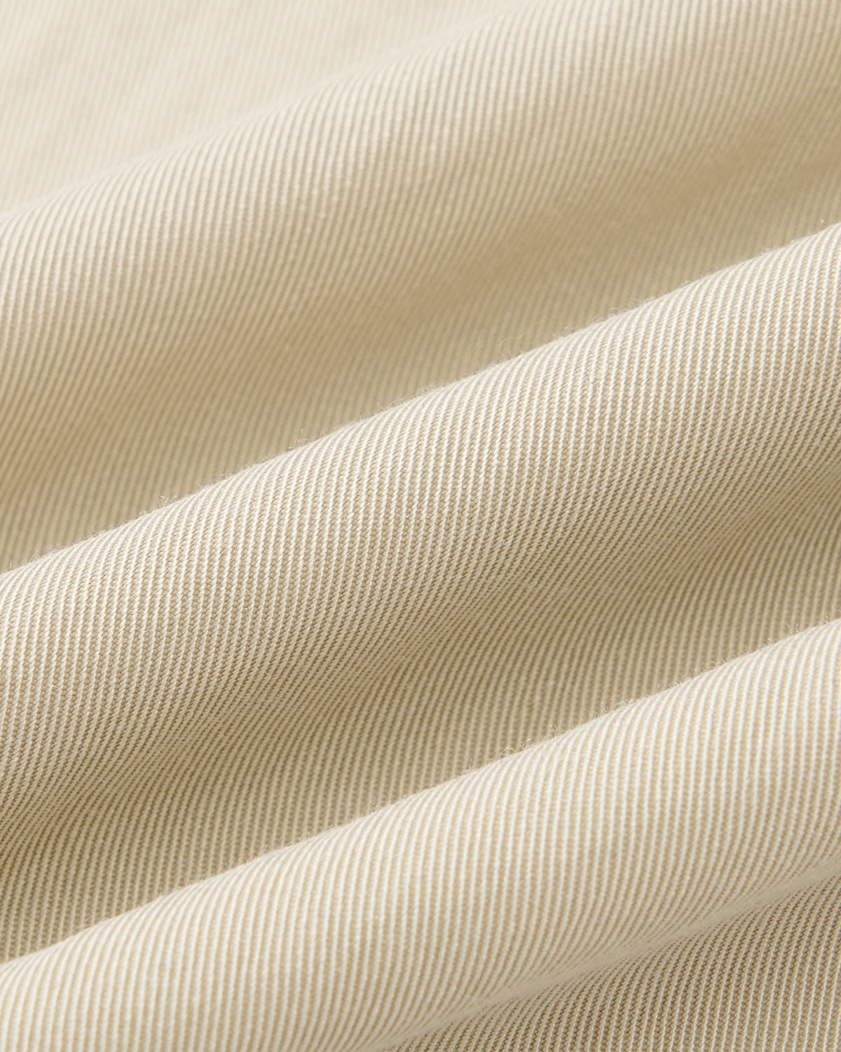 Close-up of Sundae School's IVORY HIGH NECK TIE SHIRT shows its beige fabric with fine diagonal stripes, soft folds, and textured surface—perfect for a summer-weight convertible high neck style. Lighting highlights the subtle ridges and smooth finish.