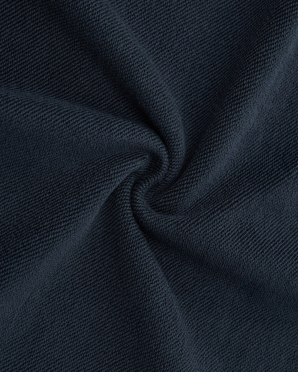 Close-up of dark navy blue textured fabric, twisted to reveal soft folds and a subtle swirl pattern—highlighting the smooth weave of Sundae School’s INDIGO WASH HANBOK HOODIE with its signature sleeve stash pocket.