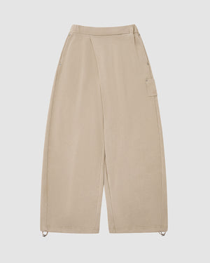 The TAUPE WRAP SWEATBAJI by Sundae School features a high waist, wide legs, side seams, one flap pocket, and ankle drawstrings. Hanbok-inspired and crafted from 100% cotton, these pants are shown laid flat on a white background.