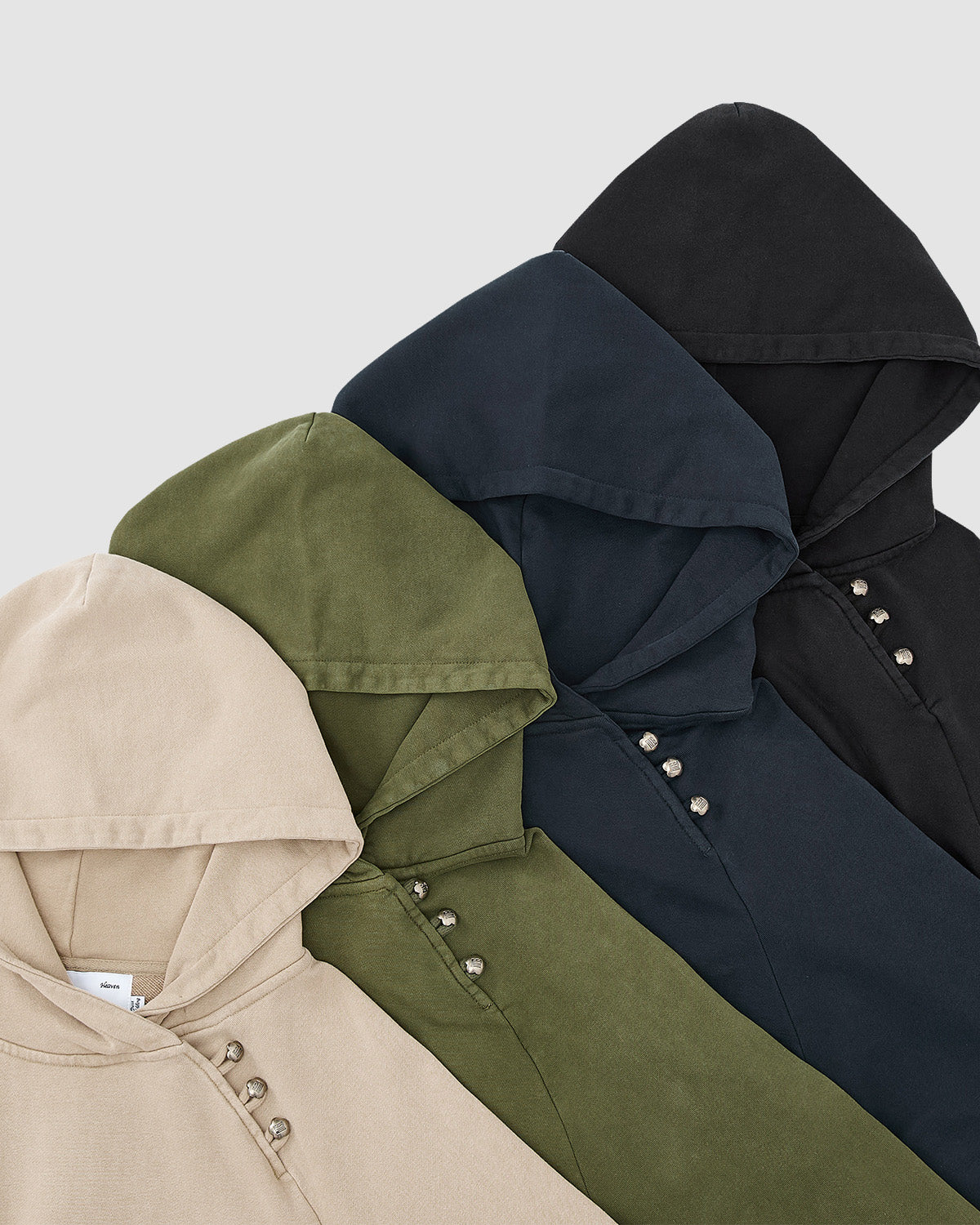 Four hooded sweatshirts, including Sundae School’s KHAKI HANBOK HOODIE, are displayed in beige, olive green, navy blue, and black. Each has unique button details near the neckline for a distinct touch.
