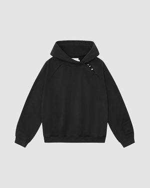 The FADE BLACK HANBOK HOODIE by Sundae School features raglan sleeves, an asymmetric hood closure, three metallic snaps on the left shoulder, and a patch detail on the left sleeve, shown against a light gray background.