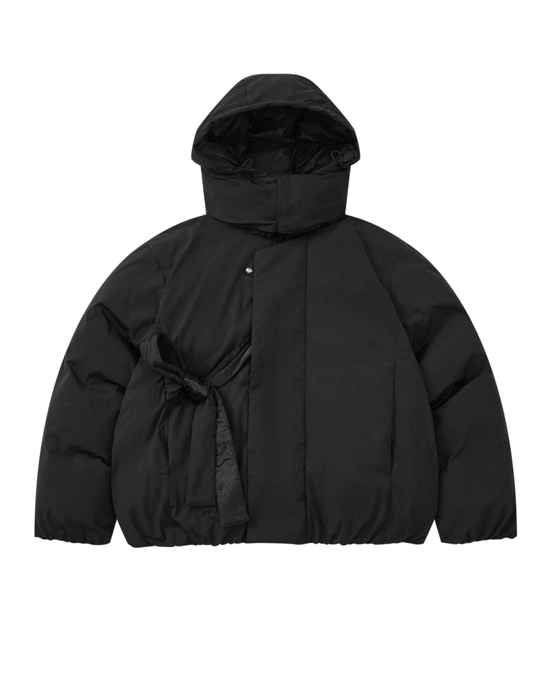 Introducing the BLACK IBUL DOWN PUFFER by Sundae School: an oversized black puffer jacket featuring a high collar, snap button closure, and a unique tied fabric belt detail on the left side of the waist. This style is designed with a detachable hood for versatile wear.