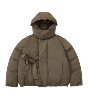 Introducing the DEEP BROWN IBUL DOWN PUFFER from Sundae School—a cocoon-style puffer jacket in deep brown featuring a hood, front zipper, snap buttons, and an asymmetrical tied belt at the waist. This jacket boasts a quilted, padded texture and long sleeves for enhanced warmth.