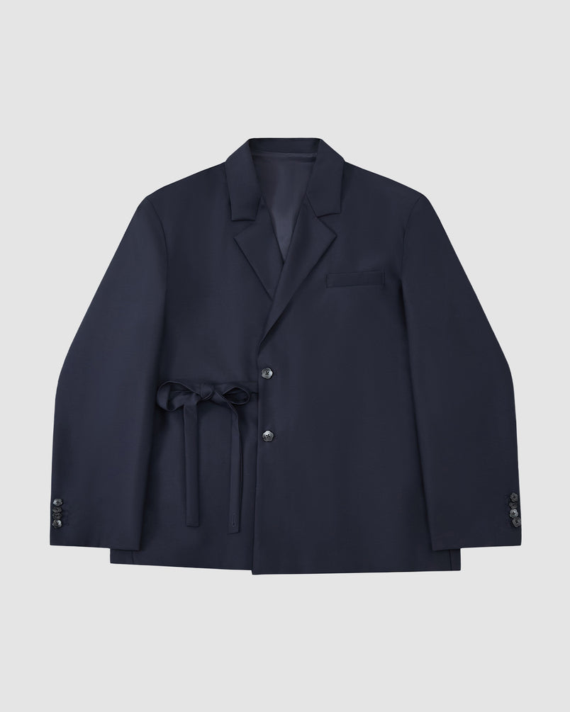 The Sundae School NAVY DOUBLE DUTY BLAZER, a navy wool blend with notched lapel, front buttons, chest pocket, and hanbok-inspired fabric belt at the waist, is displayed flat on a light gray background.