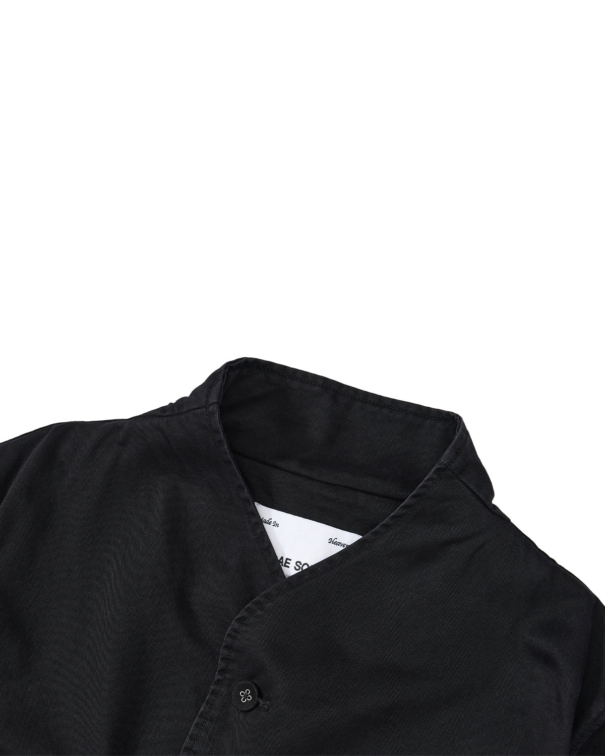 A close-up of the BLACK JEOGORI TIE JACKET by Sundae School, featuring a black collared design with a buttoned neckline inspired by a monk collar jeogori, displayed from the shoulders up against a white background. The inner label is partially visible.