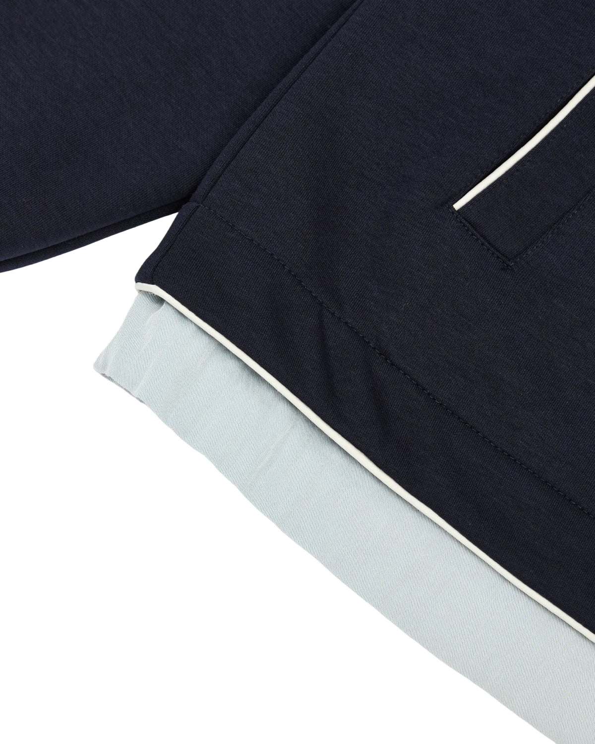 Close-up of the Sundae School NAVY PALISADE PARK TRACK JACKET, featuring a dark navy hue with white trim and pocket details layered over a light blue garment. Subtle contrast fabric accents enhance its elevated look.