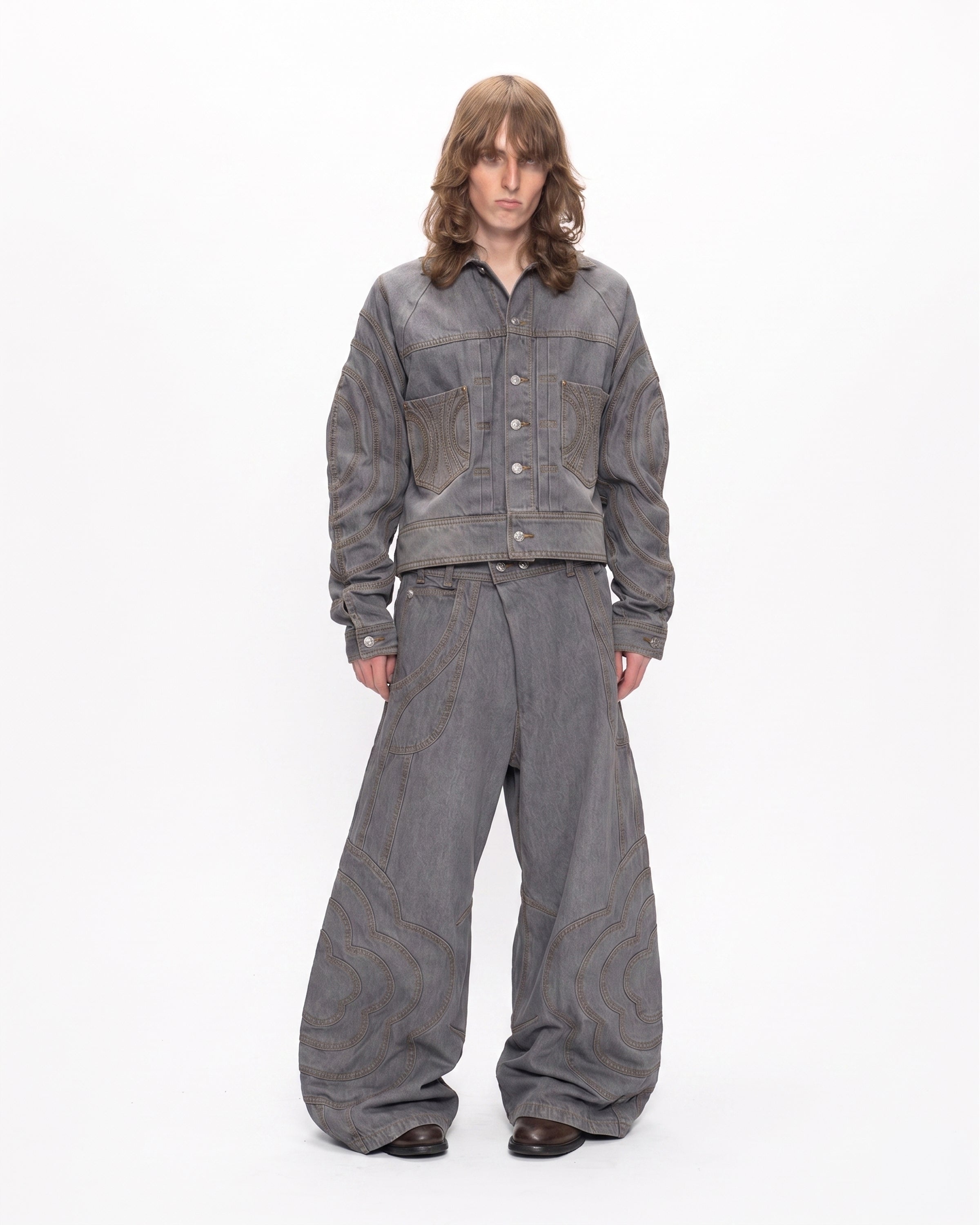 A person with long brown hair wears Sundae School's JOONIVERSE JEANS GREY and a grey denim jacket, standing against a plain white background.