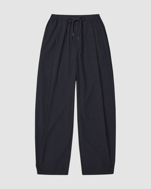 The Sundae School KIKI DRAWSTRING SLACKS are wide-leg, dark navy pinstripe sweatpants with a relaxed barrel leg and elastic drawstring waist, shown laid flat on a light gray background.