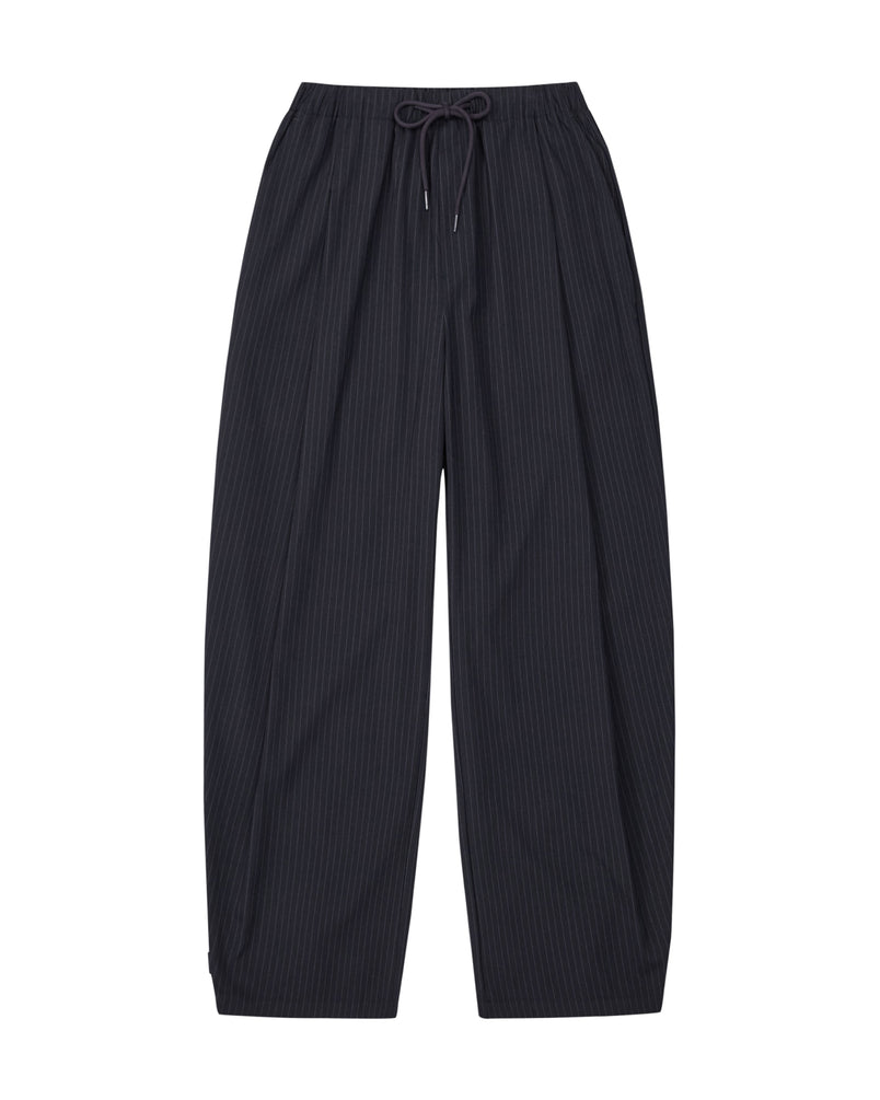 The KIKI DRAWSTRING SLACKS by Sundae School are black, loose-fitting pinstripe sweatpants featuring an elastic drawstring waist, shown flat against a white background. Their wide, straight barrel leg design delivers a relaxed fit for comfortable and effortlessly stylish wear.