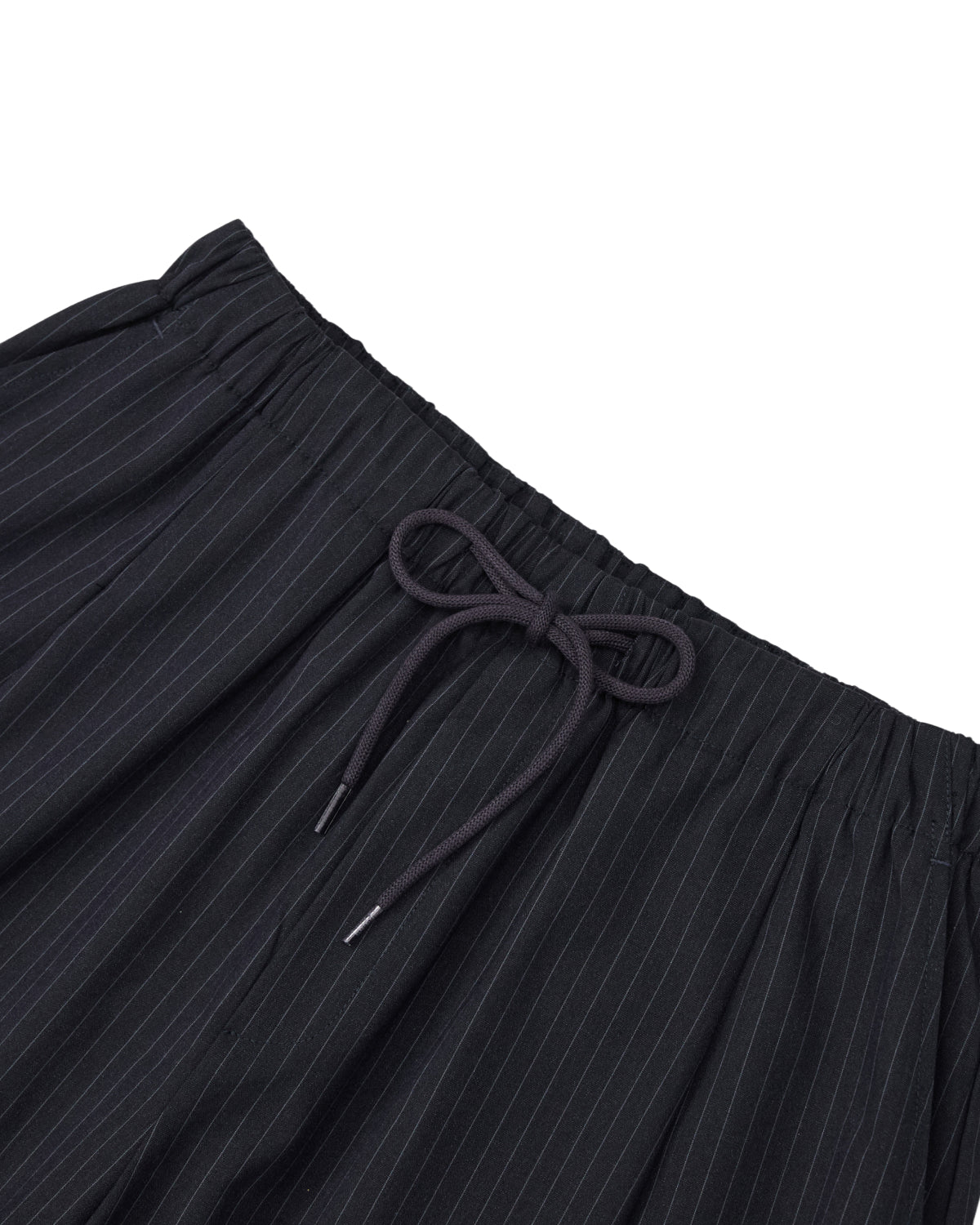Close-up of the waistband of Sundae School’s KIKI DRAWSTRING SLACKS, featuring a black elastic drawstring waist with a black drawstring tied in a bow. The lightweight fabric is adorned with thin white vertical stripes, giving these pinstriped slacks a modern yet relaxed vibe.