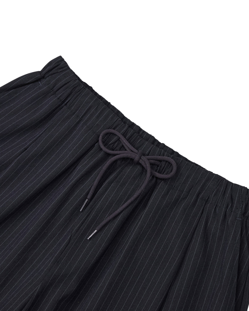 Close-up of the waistband of Sundae School’s KIKI DRAWSTRING SLACKS, featuring a black elastic drawstring waist with a black drawstring tied in a bow. The lightweight fabric is adorned with thin white vertical stripes, giving these pinstriped slacks a modern yet relaxed vibe.