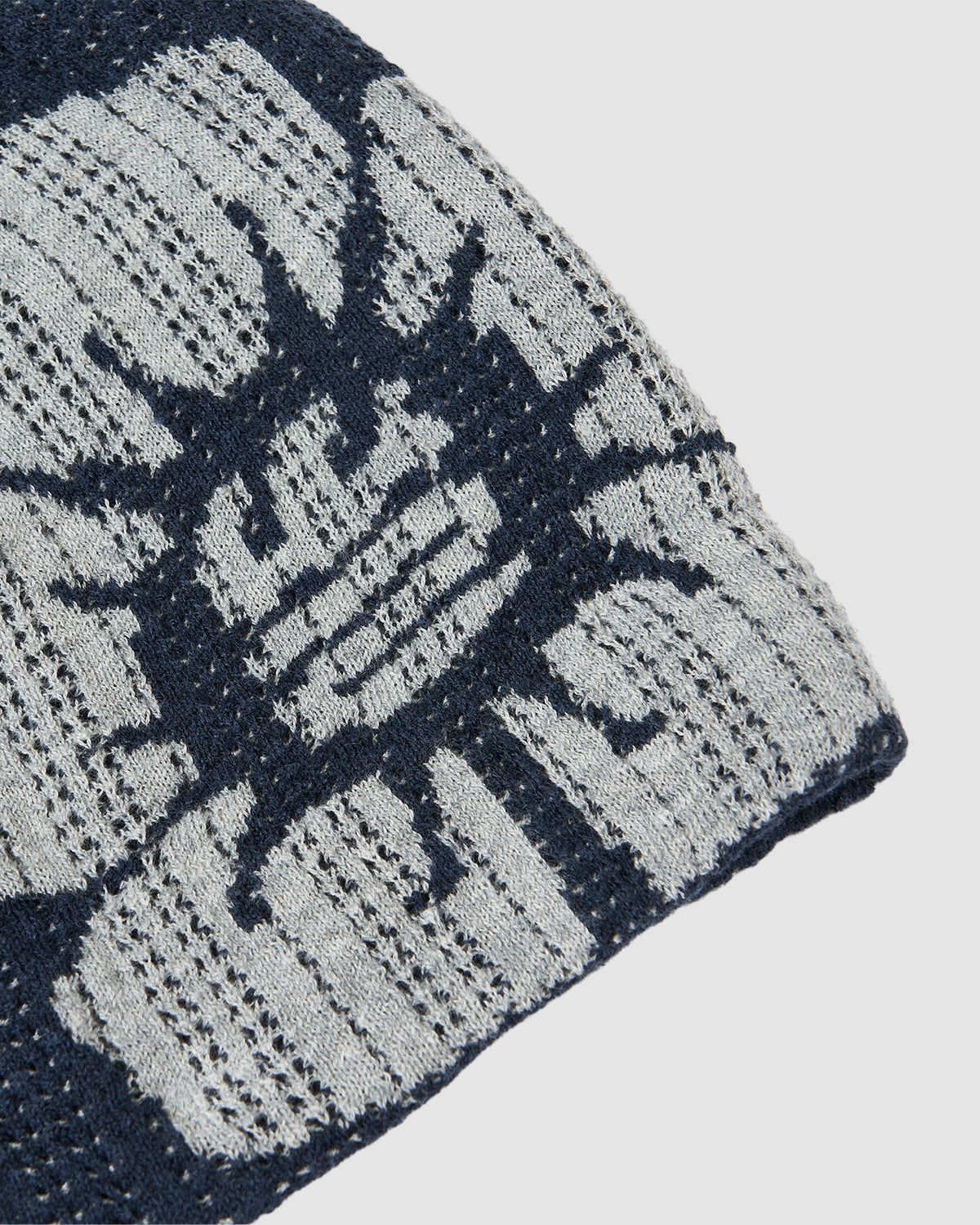 A close-up of the Sundae School NAVY DDUL KNIT BEANIE, made from cotton Jacquard mochi fabric with a navy and light gray abstract animal face pattern, shown against a plain white background.