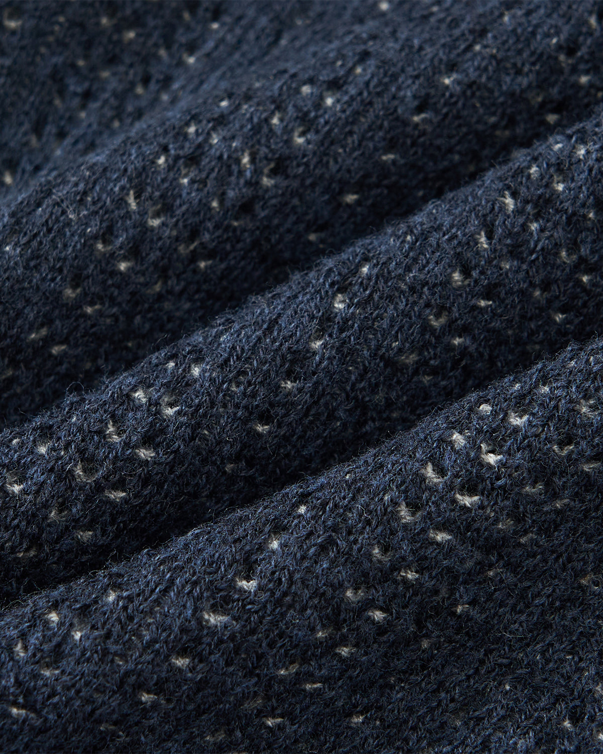 Close-up of the NAVY DDUL KNIT BEANIE by Sundae School, showcasing its dark blue cotton jacquard knit with a textured pattern and small white specks, highlighting the detailed stitches and fibers.