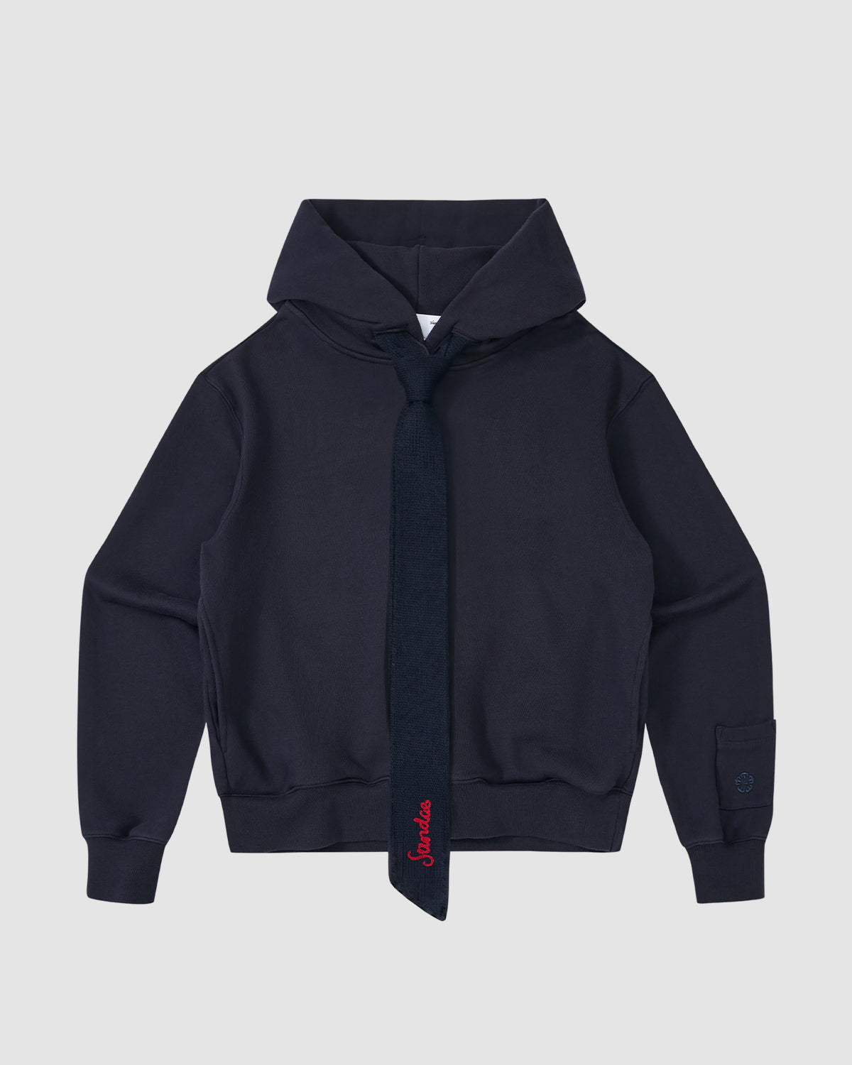 The NAVY KNIT TIE HOODIE by Sundae School is a heavyweight brushed cotton hoodie in navy, featuring a matching knit tie with red embroidery, ribbed cuffs and waistband, shown against a light gray background.