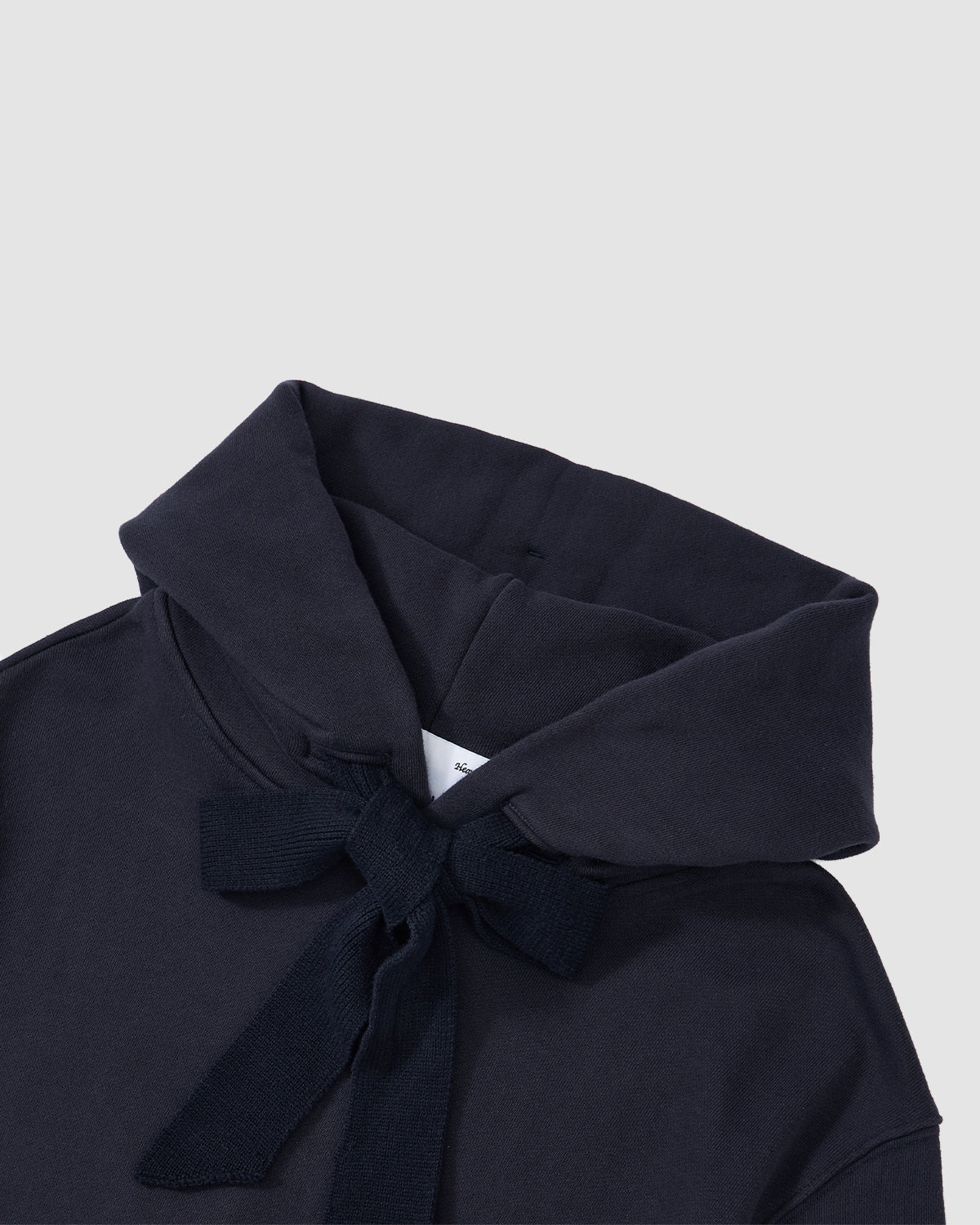 A close-up of the Sundae School NAVY KNIT TIE HOODIE with a crossover collar and matching fabric tie at the neckline, laid flat on a light gray background.
