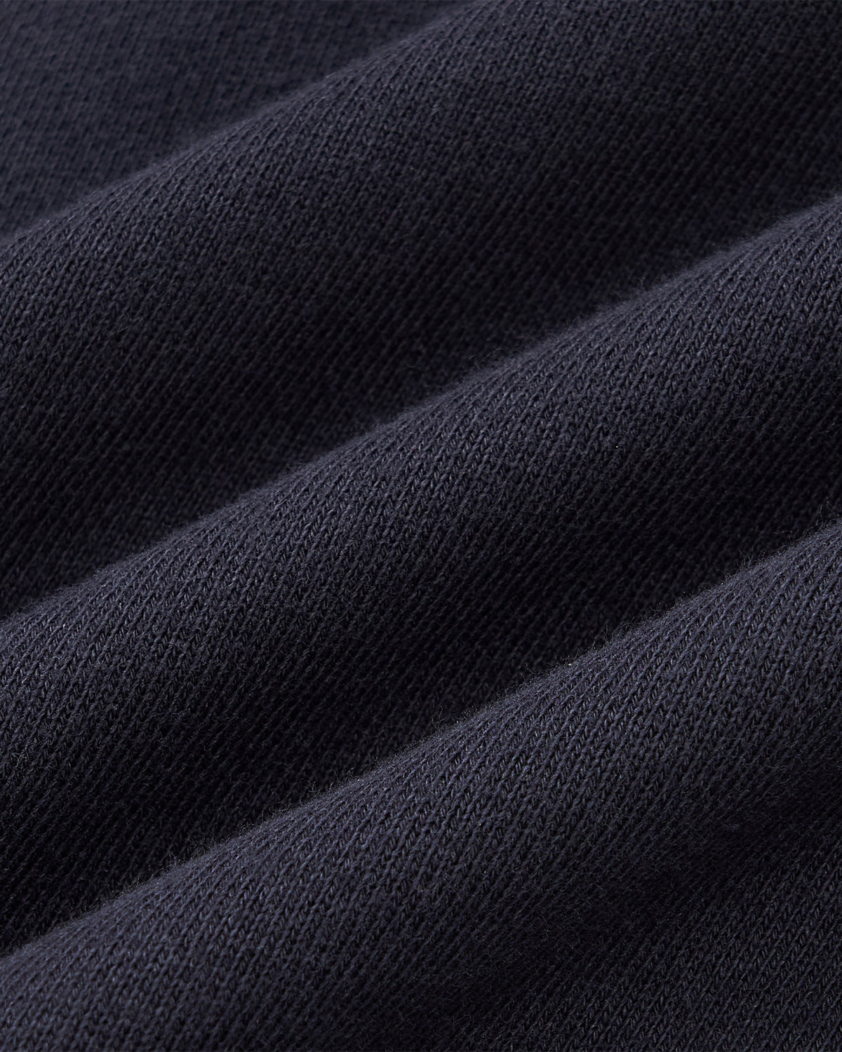 Close-up of Sundae School NAVY KNIT TIE HOODIE fabric, showcasing its heavyweight, visible knit texture arranged in gentle diagonal folds.