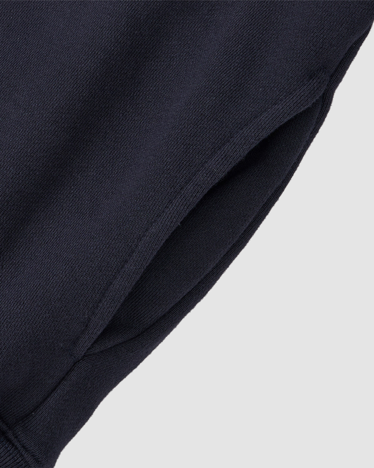 Close-up of the Sundae School NAVY KNIT TIE HOODIE, highlighting its side pocket and soft brushed cotton finish, set against a light gray background.