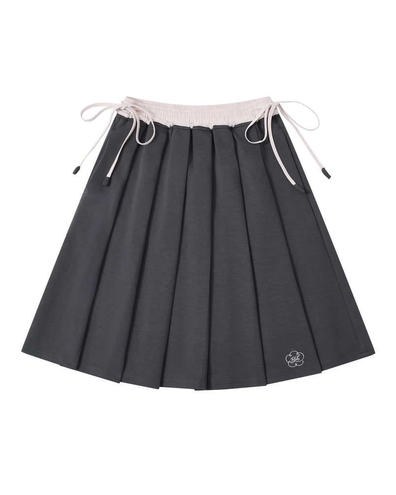 The CHARCOAL KONA MIDI SKIRT by Sundae School is a dark gray pleated skirt featuring a light pink drawstring waistband and a small embroidered bear face near the hem.