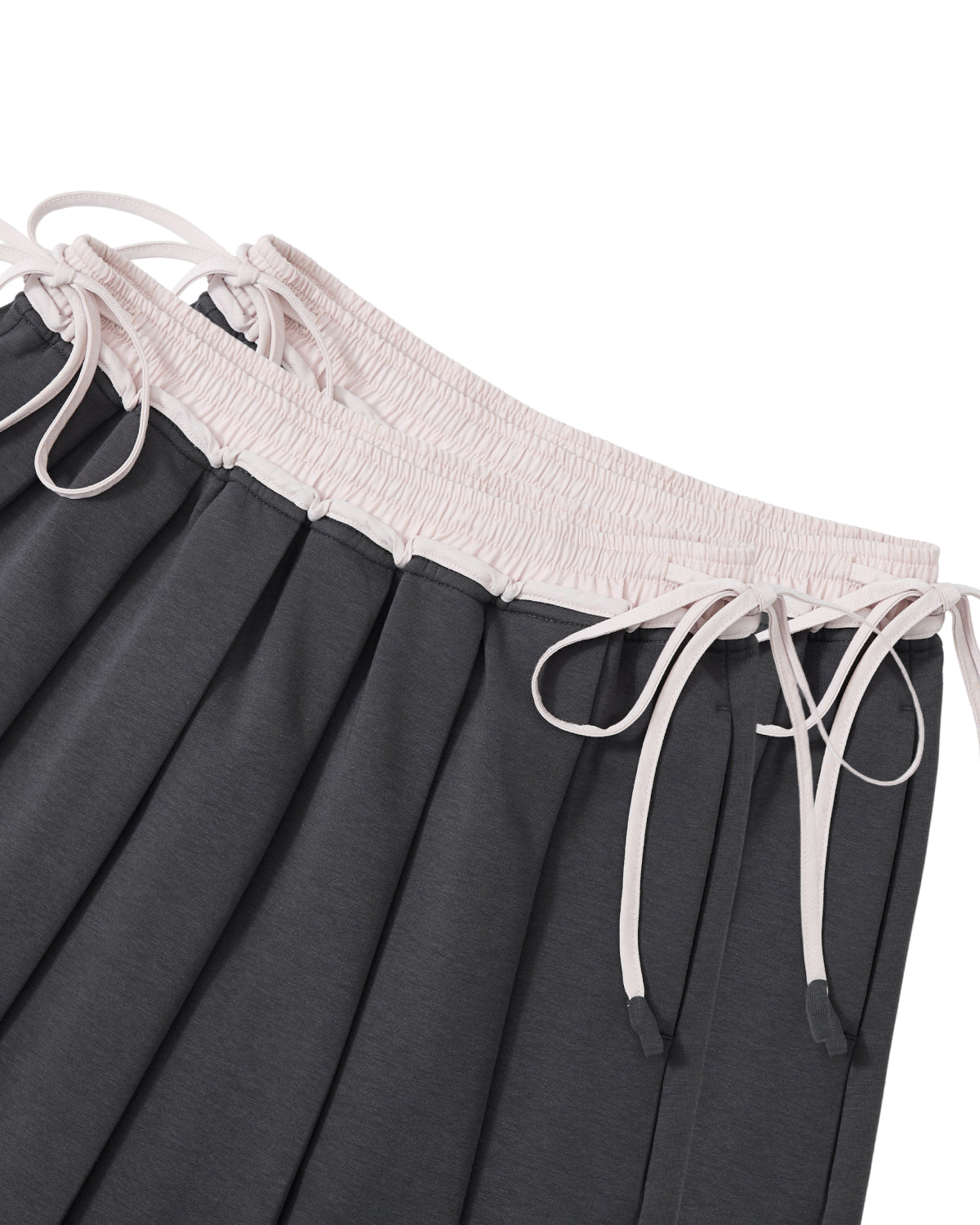 Two CHARCOAL KONA MIDI SKIRTS by Sundae School, featuring pleated dark gray fabric with light pink elastic waistbands and matching drawstrings, are shown overlapping each other on a white background.