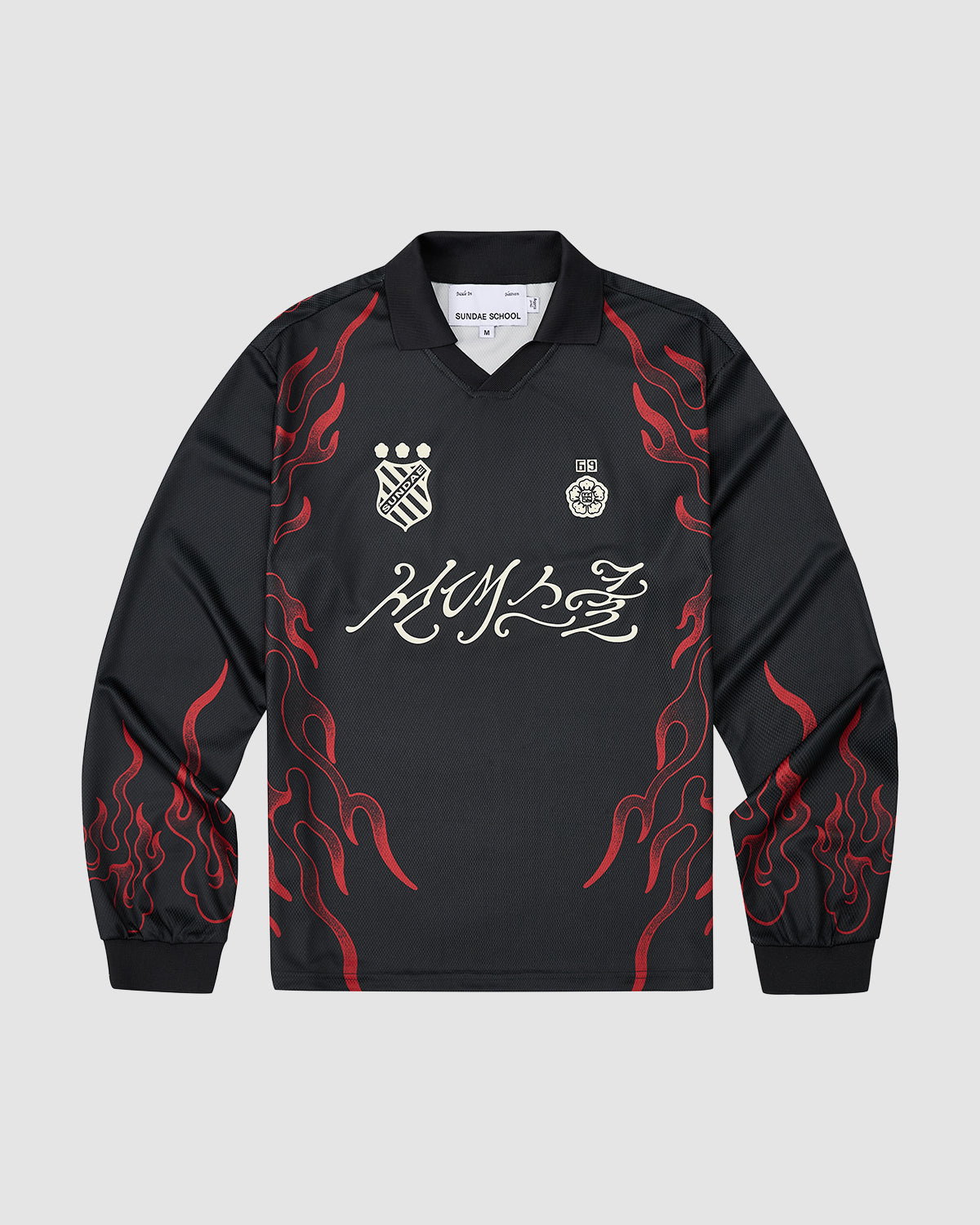 The Sundae School KOREATOWN FOOTBALL JERSEY is a black long-sleeve shirt with red flame graphics on the sleeves and sides, white embroidered chest logos, bold white script across the front, and custom Korean designs inspired by K-Town style.