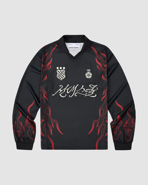 The Sundae School KOREATOWN FOOTBALL JERSEY is a black long-sleeve shirt with red flame graphics on the sleeves and sides, white embroidered chest logos, bold white script across the front, and custom Korean designs inspired by K-Town style.