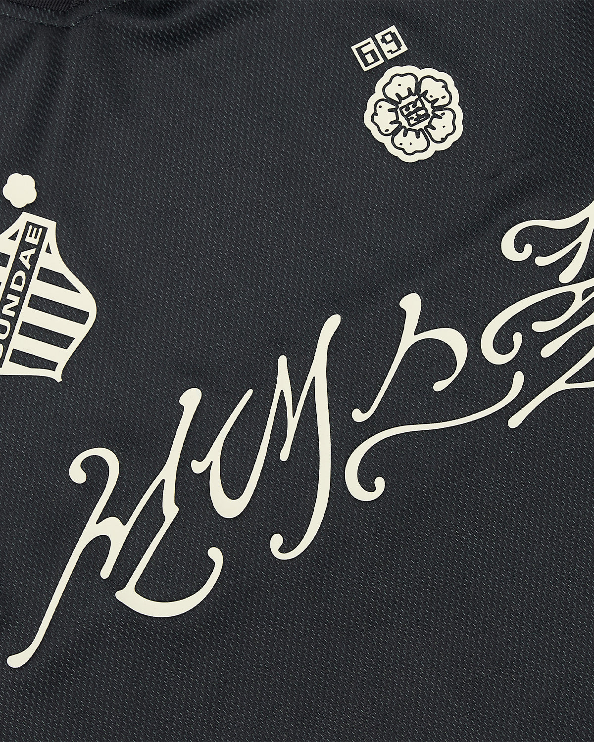 The KOREATOWN FOOTBALL JERSEY from Sundae School features black fabric with white Korean graphics, stylized text, a SUNDAE badge, 69 flower emblem, and decorative swirls—ideal for K-Town fashion fans.