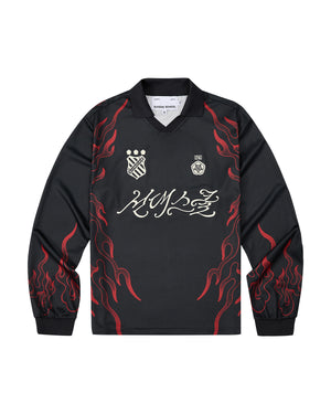 Sundae School’s KOREATOWN FOOTBALL JERSEY features black long sleeves accented with red flame designs along the sleeves and sides, white logos and badges on the chest, and bold stylized calligraphy across the front—a striking piece inspired by K-Town fashion, perfect for fans of custom lettered apparel.