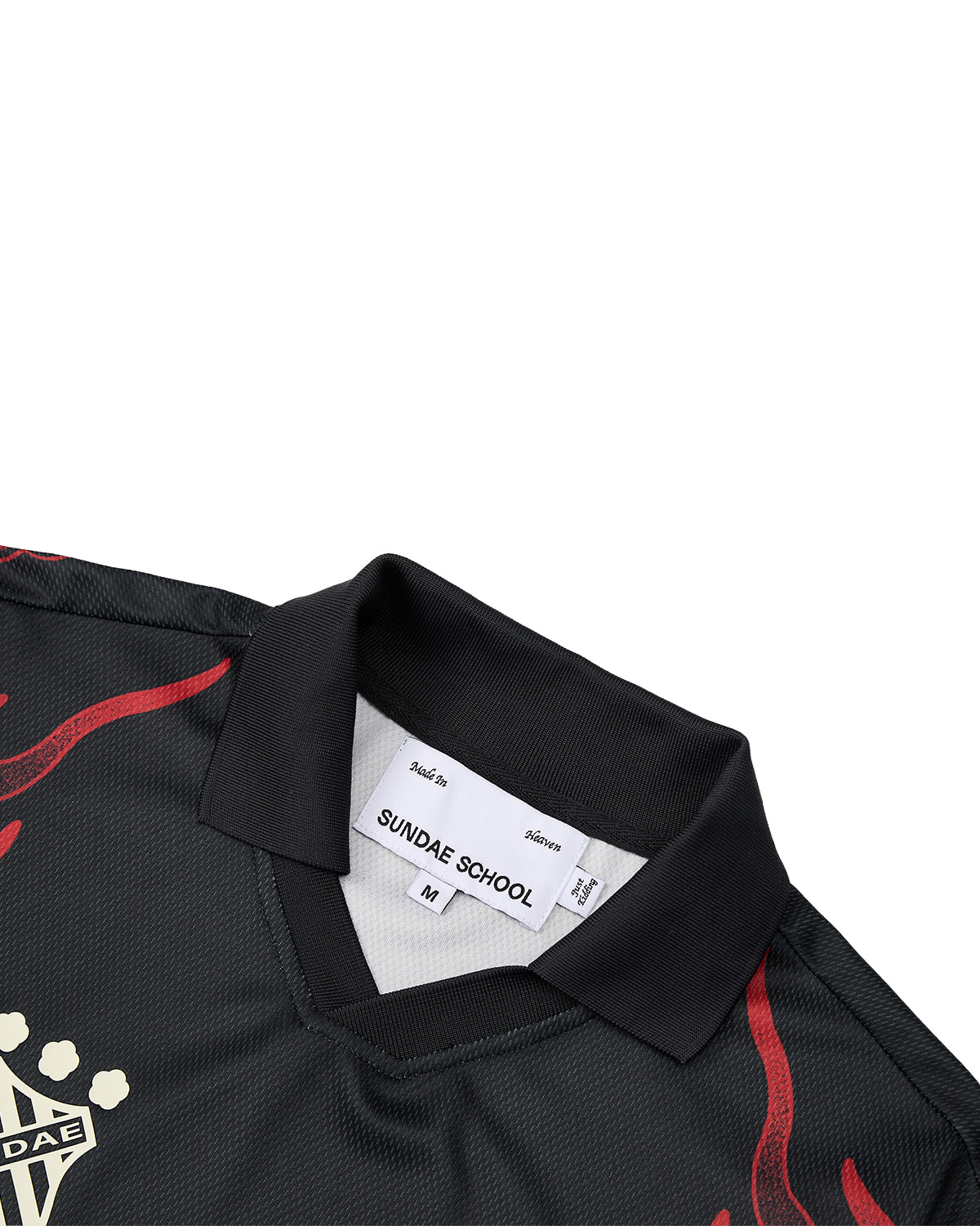 A close-up of the KOREATOWN FOOTBALL JERSEY by Sundae School, featuring a black collared design with bold red detailing and a visible label that reads SUNDAE SCHOOL M. The jersey’s woven texture and partial beige graphic on the front capture the vibrant spirit of K-Town fashion with custom calligraphy-inspired accents.