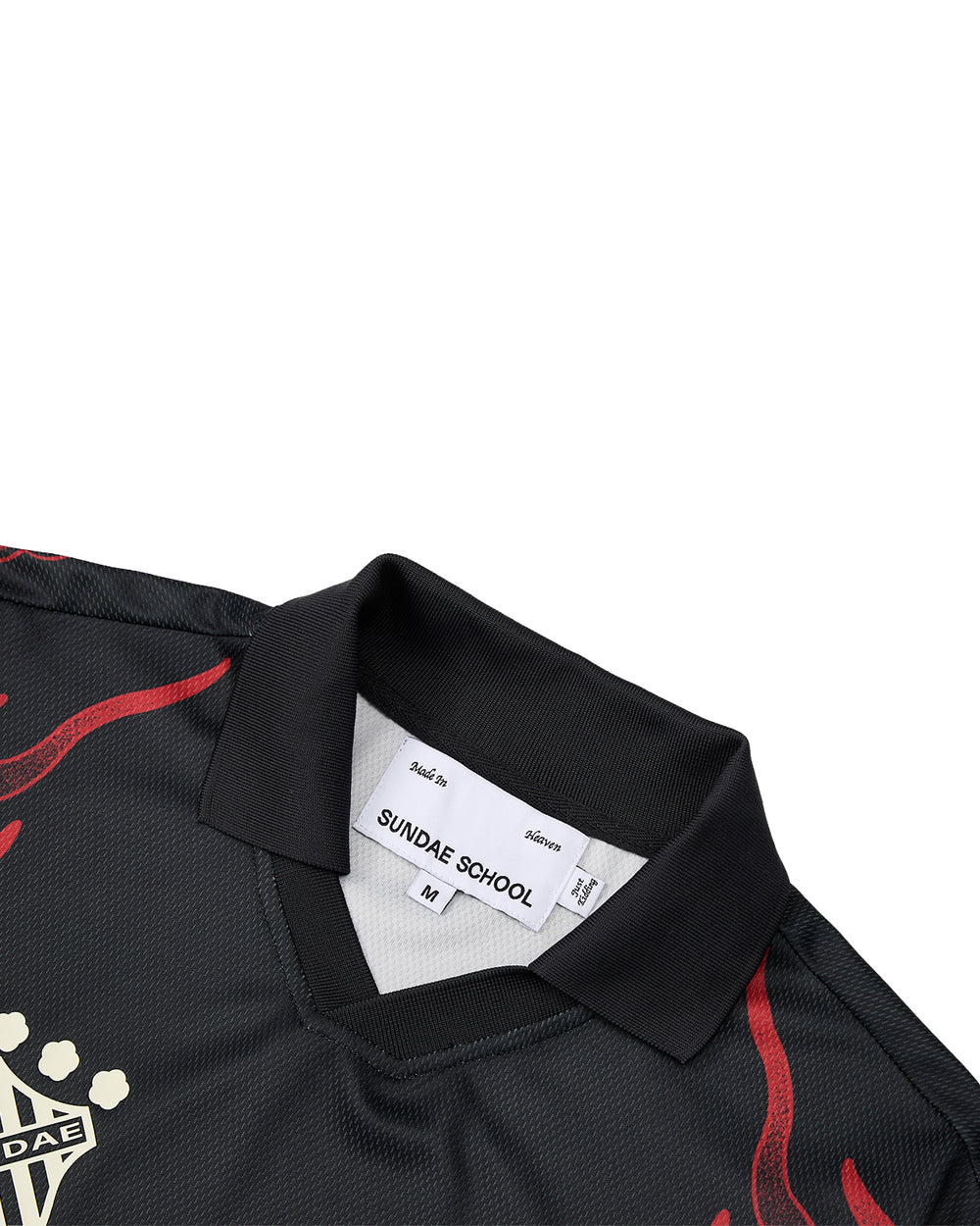 A close-up of the KOREATOWN FOOTBALL JERSEY by Sundae School, featuring a black collared design with bold red detailing and a visible label that reads SUNDAE SCHOOL M. The jersey’s woven texture and partial beige graphic on the front capture the vibrant spirit of K-Town fashion with custom calligraphy-inspired accents.
