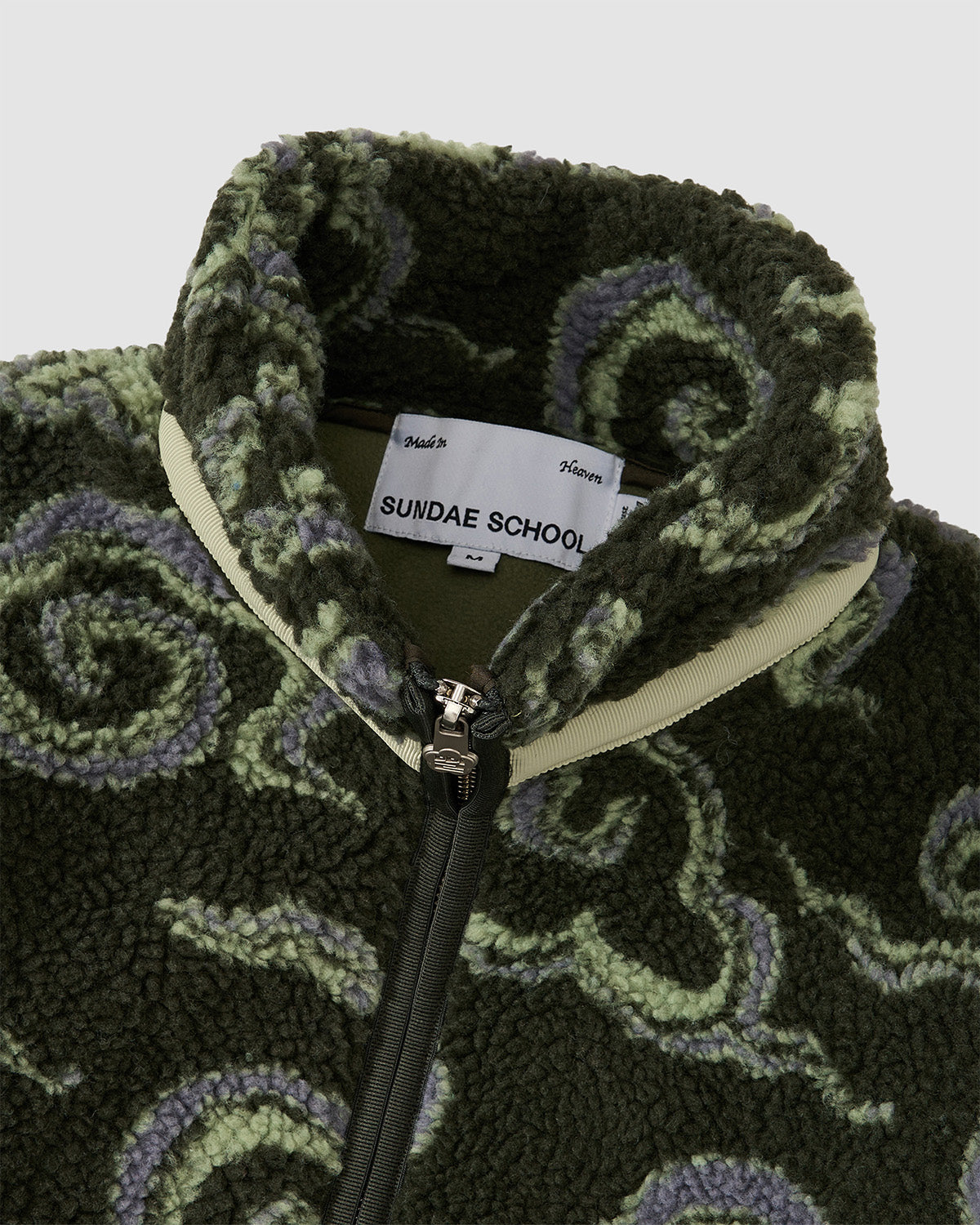 Close-up detail of the Kloud Fleece Zip-Up collar area showing the Sundae School brand label and cream-colored trim around the zip-up collar.