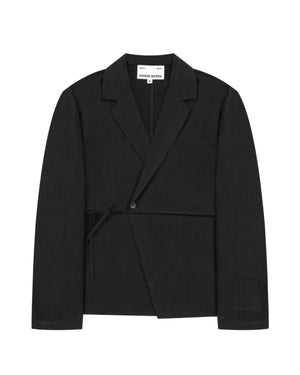 The Sundae School BLACK LINEN GORUM BLAZER is an unstructured black wrap-style blazer featuring a single button, left chest pocket, and a tie closure at the waist, displayed against a white background.