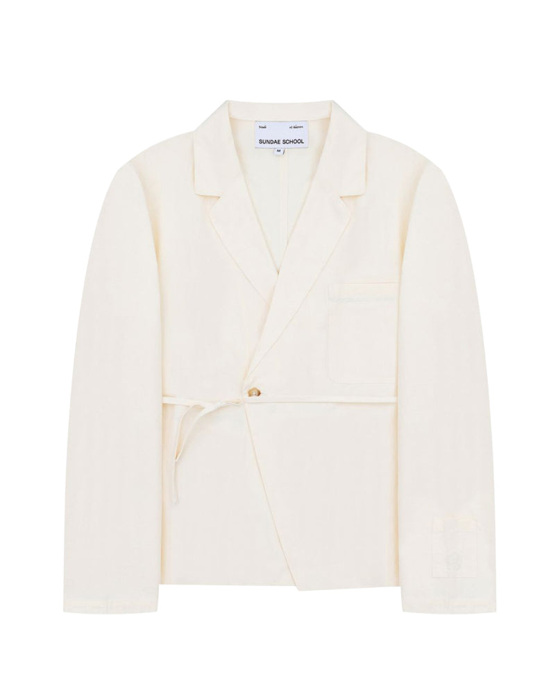 An ivory linen “Gorum Blazer” by Sundae School, featuring a single button closure, tied fabric belt, notched lapels, and a chest pocket. The label inside reads Sundae School.