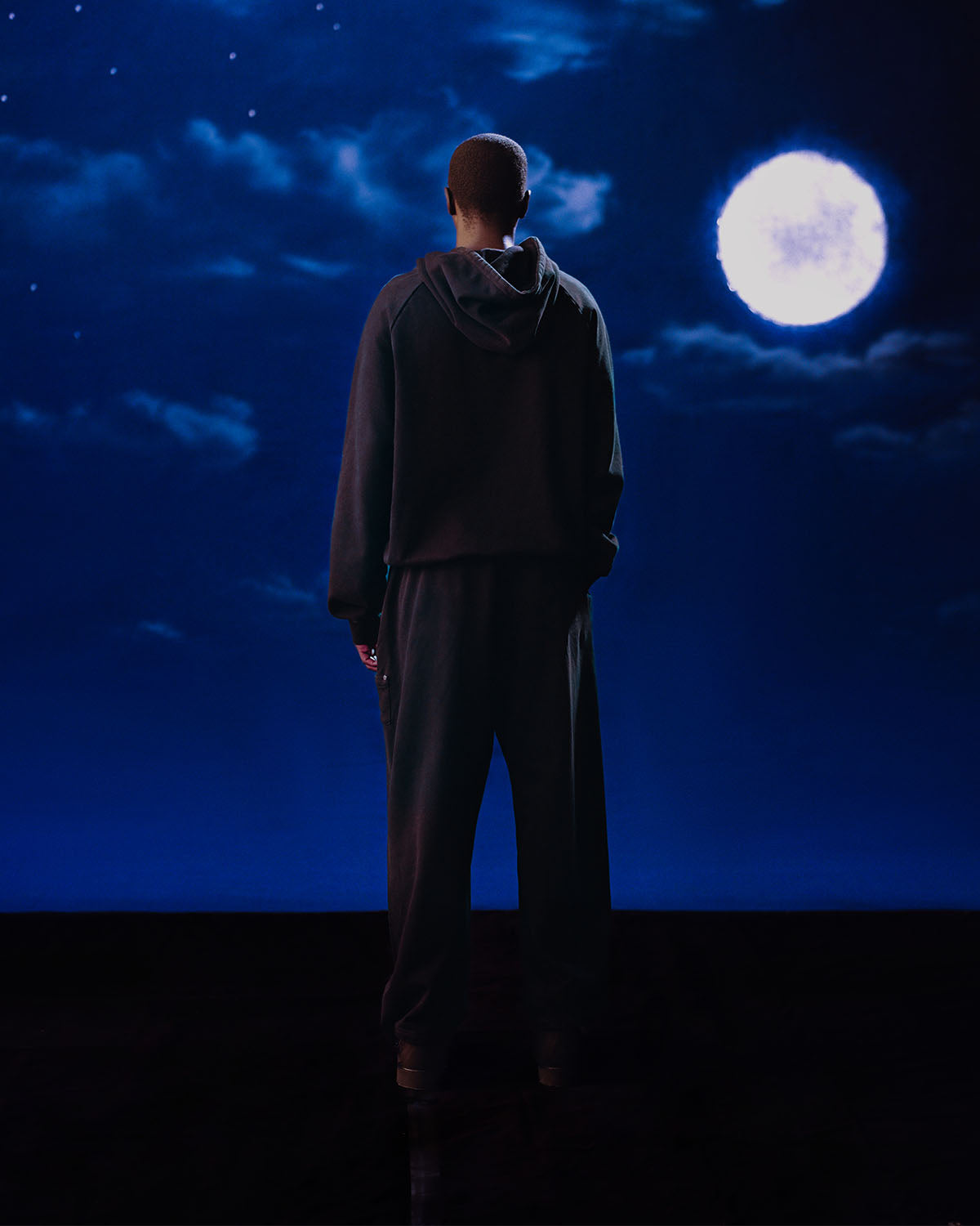 A person in dark clothing wears the Sundae School FADE BLACK HANBOK HOODIE, featuring a custom 