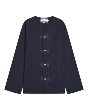The MAEHWA COLLARLESS SHIRT by Sundae School is a navy blue, long-sleeve mid-layer featuring a V-neck, frog closures, and a single chest pocket. This versatile unisex piece is displayed laid flat on a white background.