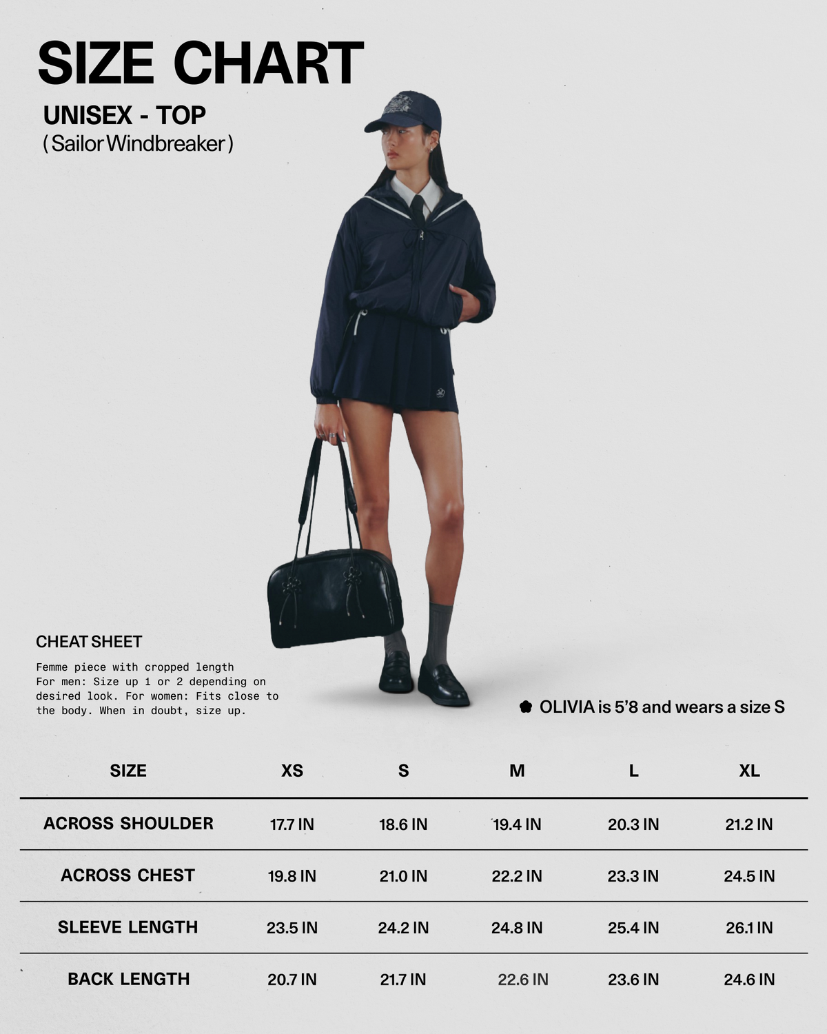 A woman stands holding a black bag, dressed in the Sundae School NAVY SAILOR WINDBREAKER, paired with a white shirt, navy skirt, sailor hat, and black shoes. A size chart and measurements for the unisex NAVY SAILOR WINDBREAKER are displayed beside her.