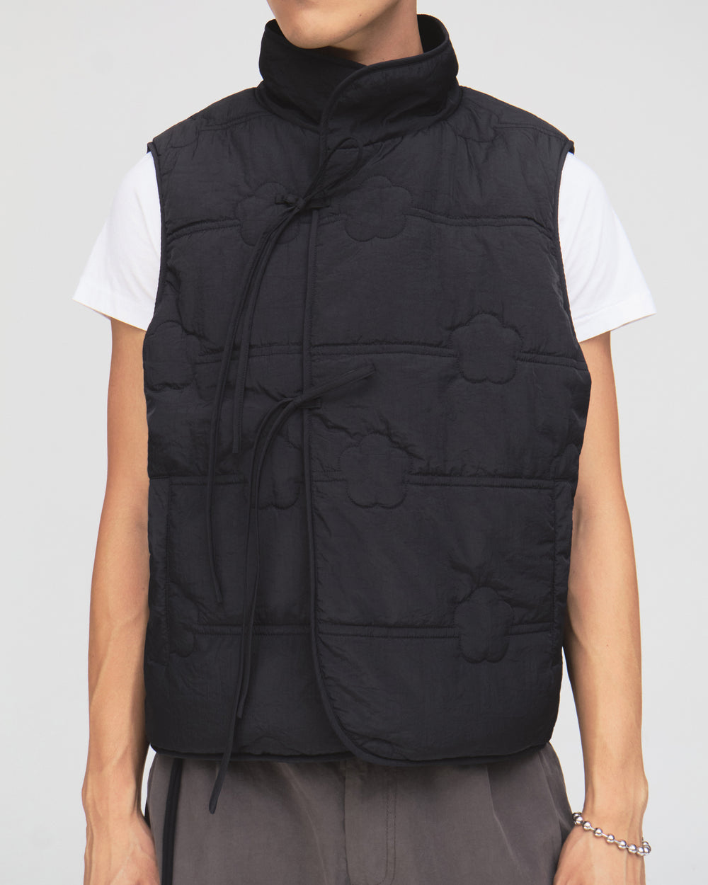 A person is wearing the BLACK MOMO REVERSIBLE FLEECE VEST by Sundae School over a white t-shirt and gray pants, standing against a plain background.