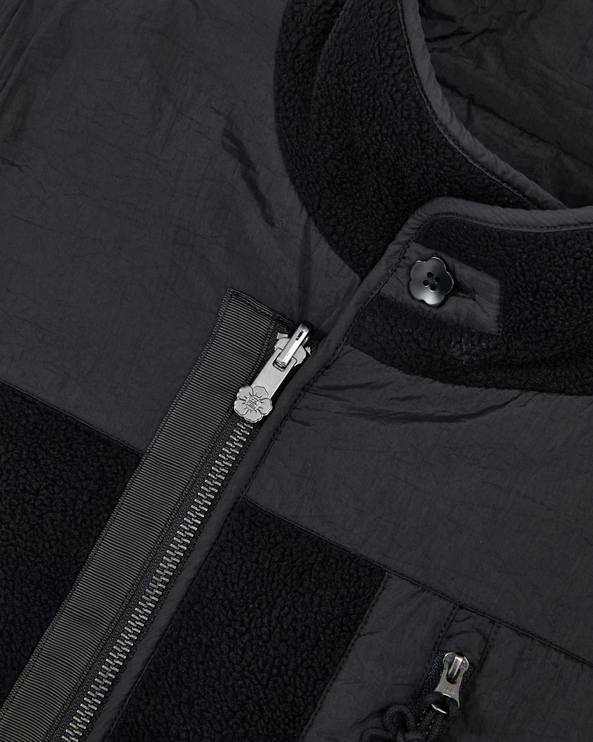 Close-up of the BLACK MOMO REVERSIBLE FLEECE VEST by Sundae School, highlighting the silver zipper, detailed fabric texture, snap button at the collar, and contrasting materials featuring both smooth and fleece sections.