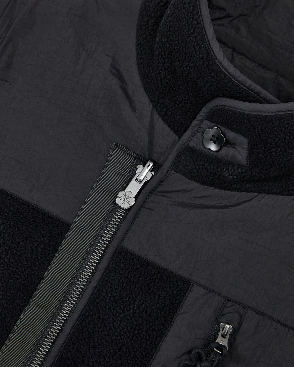 Close-up of the BLACK MOMO REVERSIBLE FLEECE VEST by Sundae School, highlighting the silver zipper, detailed fabric texture, snap button at the collar, and contrasting materials featuring both smooth and fleece sections.
