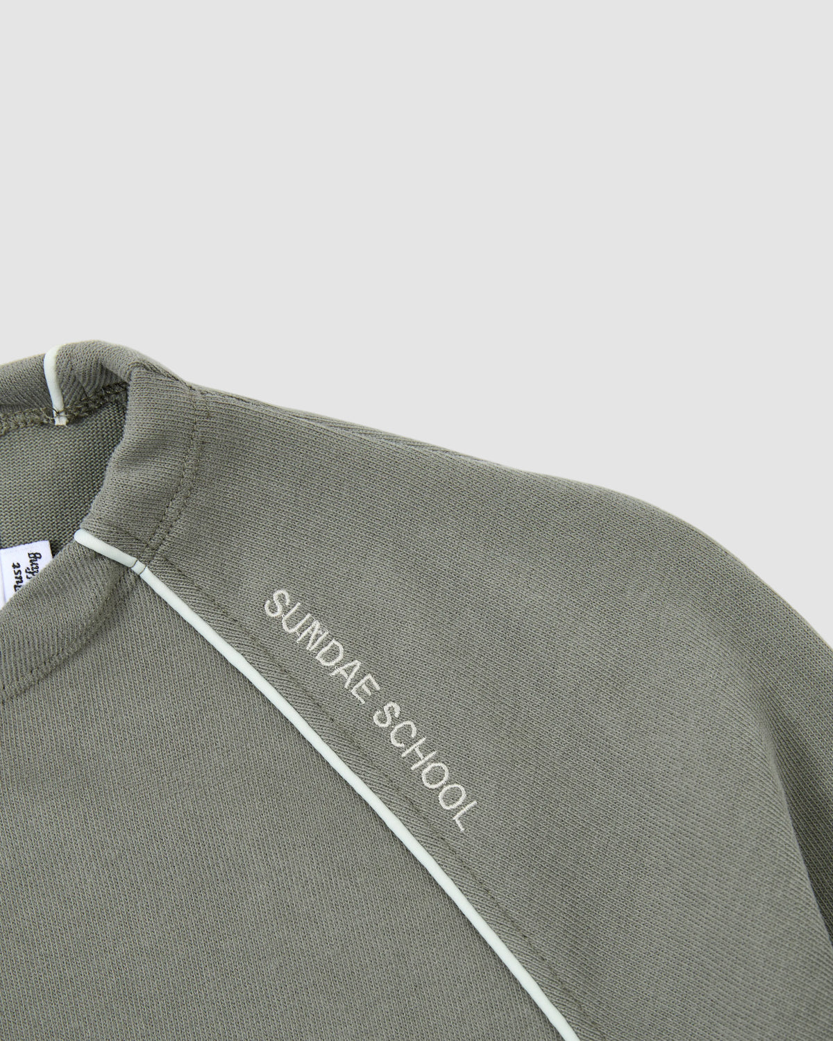 A close-up of the KHAKI OFFICE QUARTER ZIP by Sundae School, an olive green sweatshirt with white 