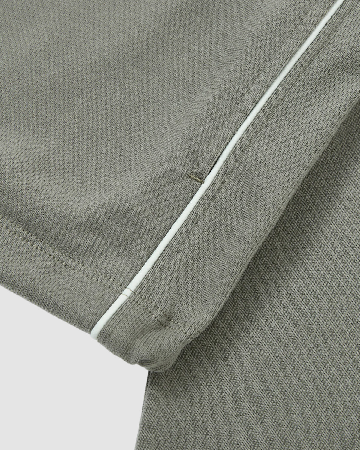 Close-up of the Sundae School KHAKI OFFICE QUARTER ZIP, highlighting its khaki green cotton jersey fabric, white seam stripe detail, and intricate stitching.