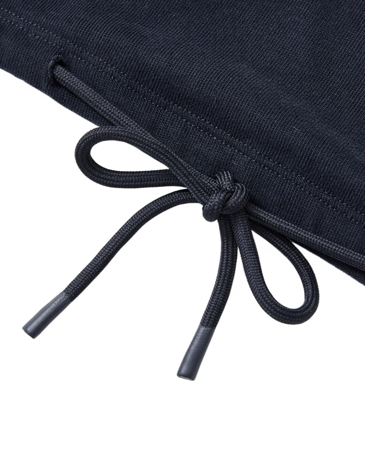 A close-up of the black drawstring, finished with metal tips and tied in a bow, on the dark cotton jersey fabric of the Sundae School NAVY OFFICE QUARTER ZIP.