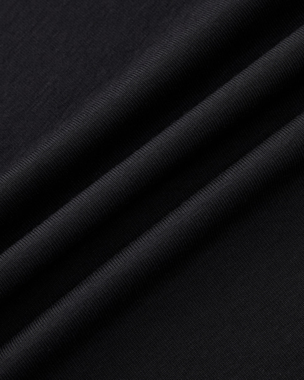 Close-up of the BLACK ORIGAMI GORUM TEE by Sundae School, featuring folded black fabric with visible texture and soft ridges that highlight its smooth and slightly ribbed surface.