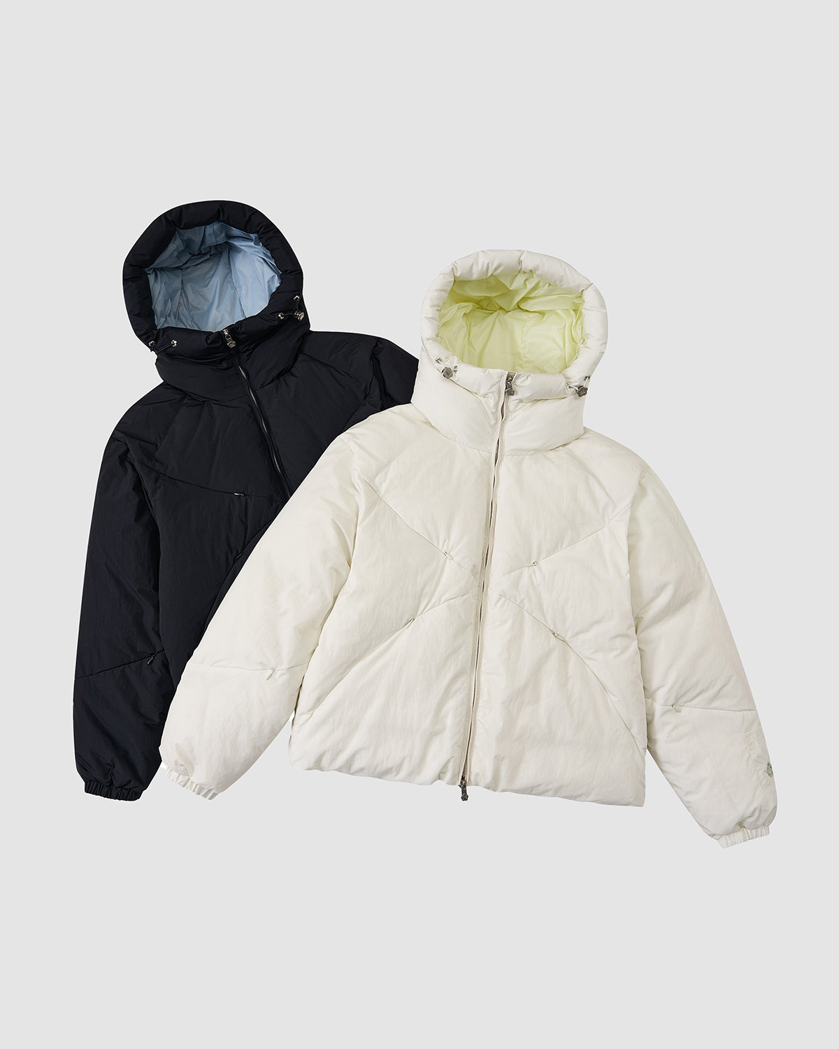 The IVORY LIME ORIGAMI PUFFER by Sundae School is displayed on a light gray background, featuring a white exterior with light green lining and hood, front zipper, and long sleeves.